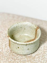 Speckled ceramic cup on a textured surface 