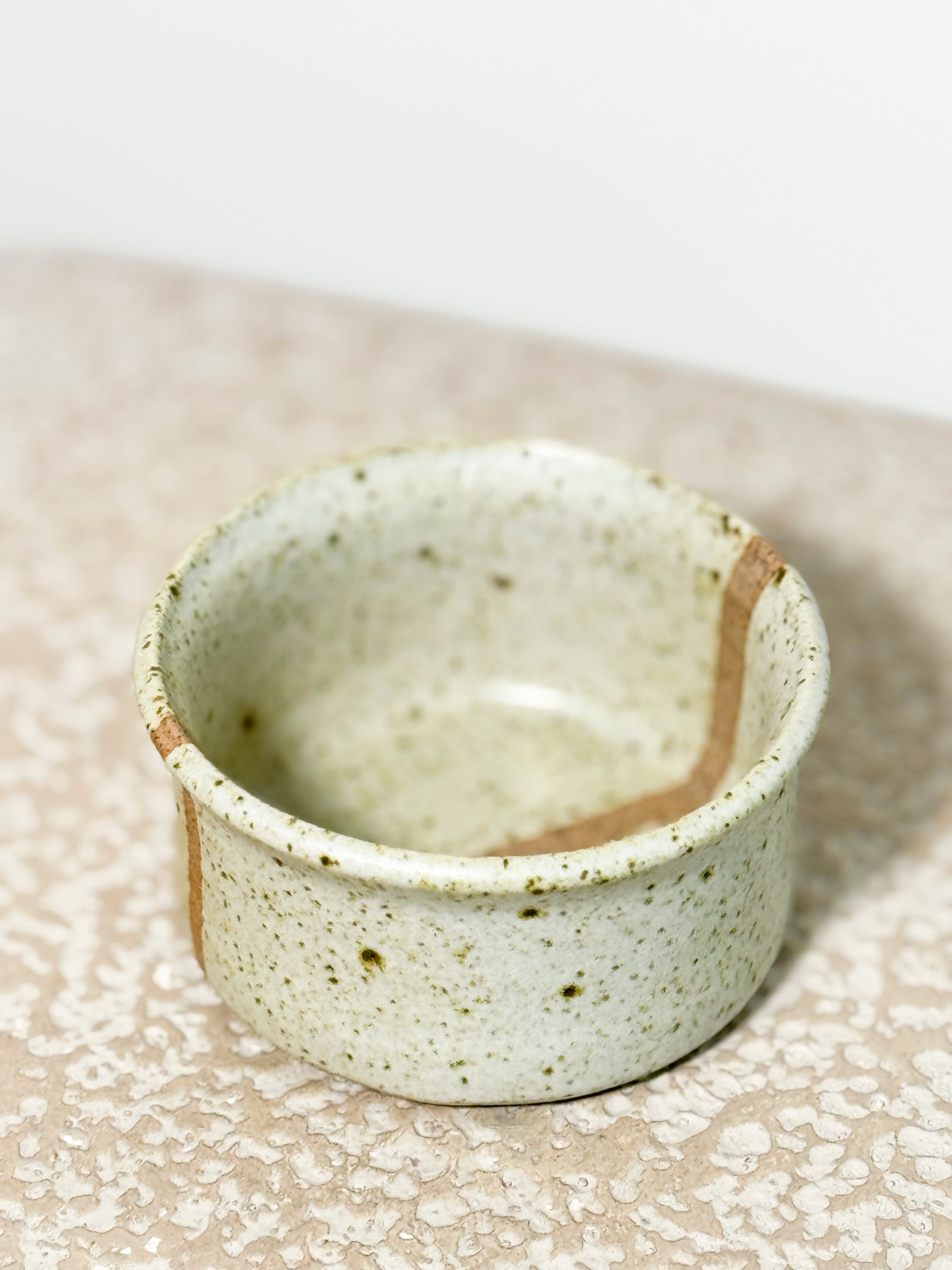 Speckled ceramic cup on a textured surface 