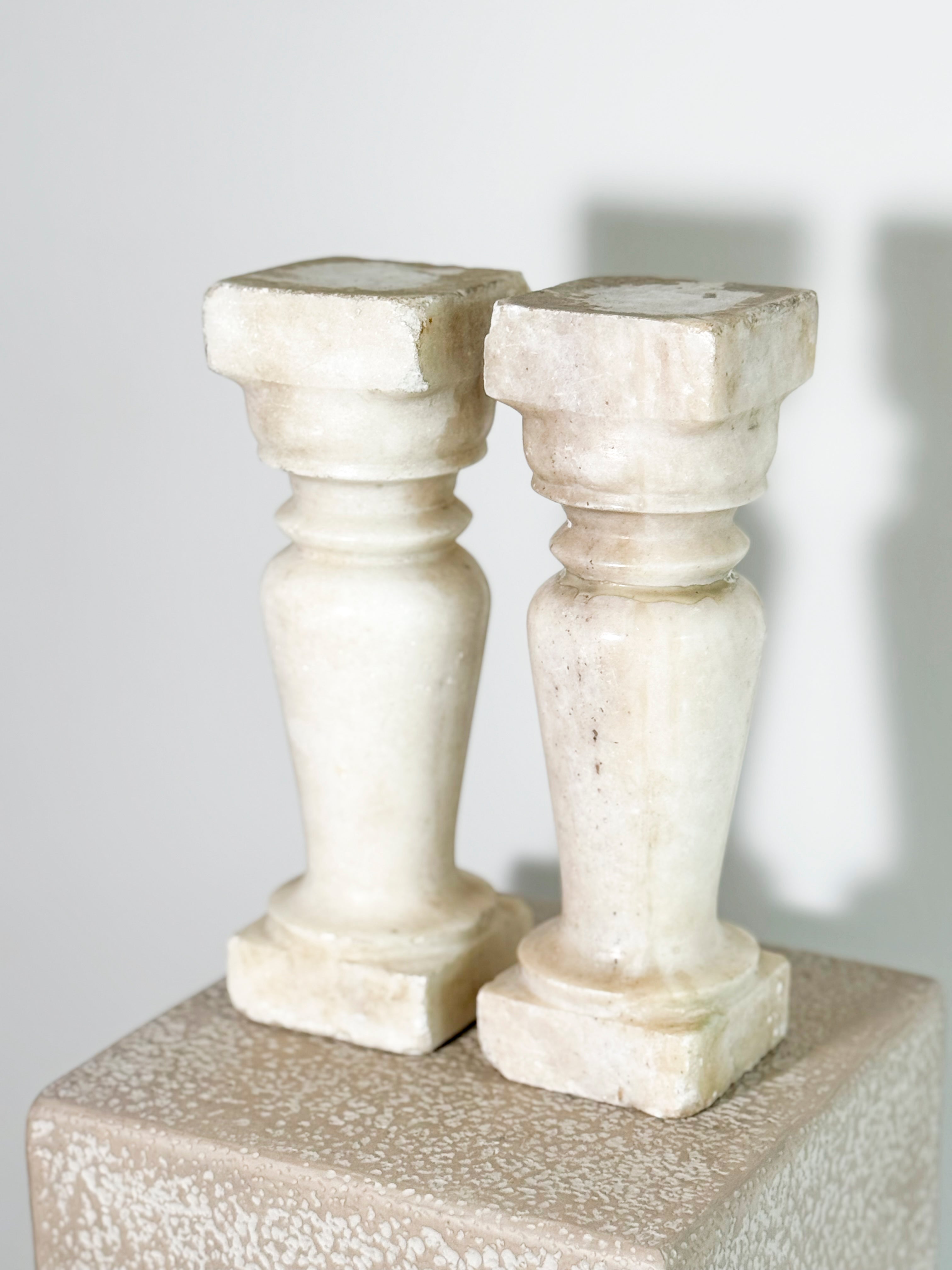 Beautiful pair of aged, handcrafted marble balusters. These are the perfect candle holders. Worn - as seen in images with one baluster showing repairs.