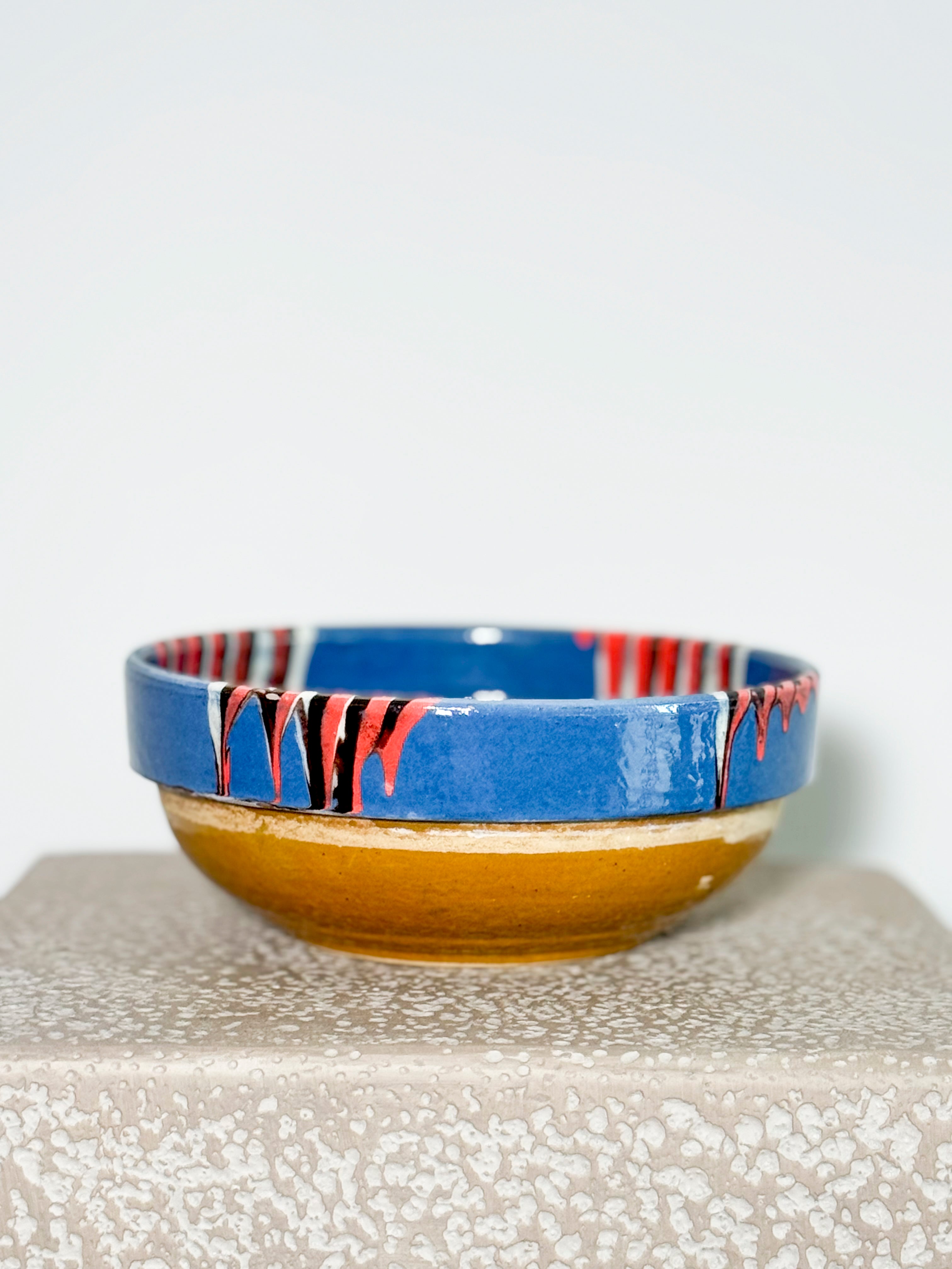 Romanian Slipware Folk bowl. Ceramic bowl with blue and red abstract design on a textured surface