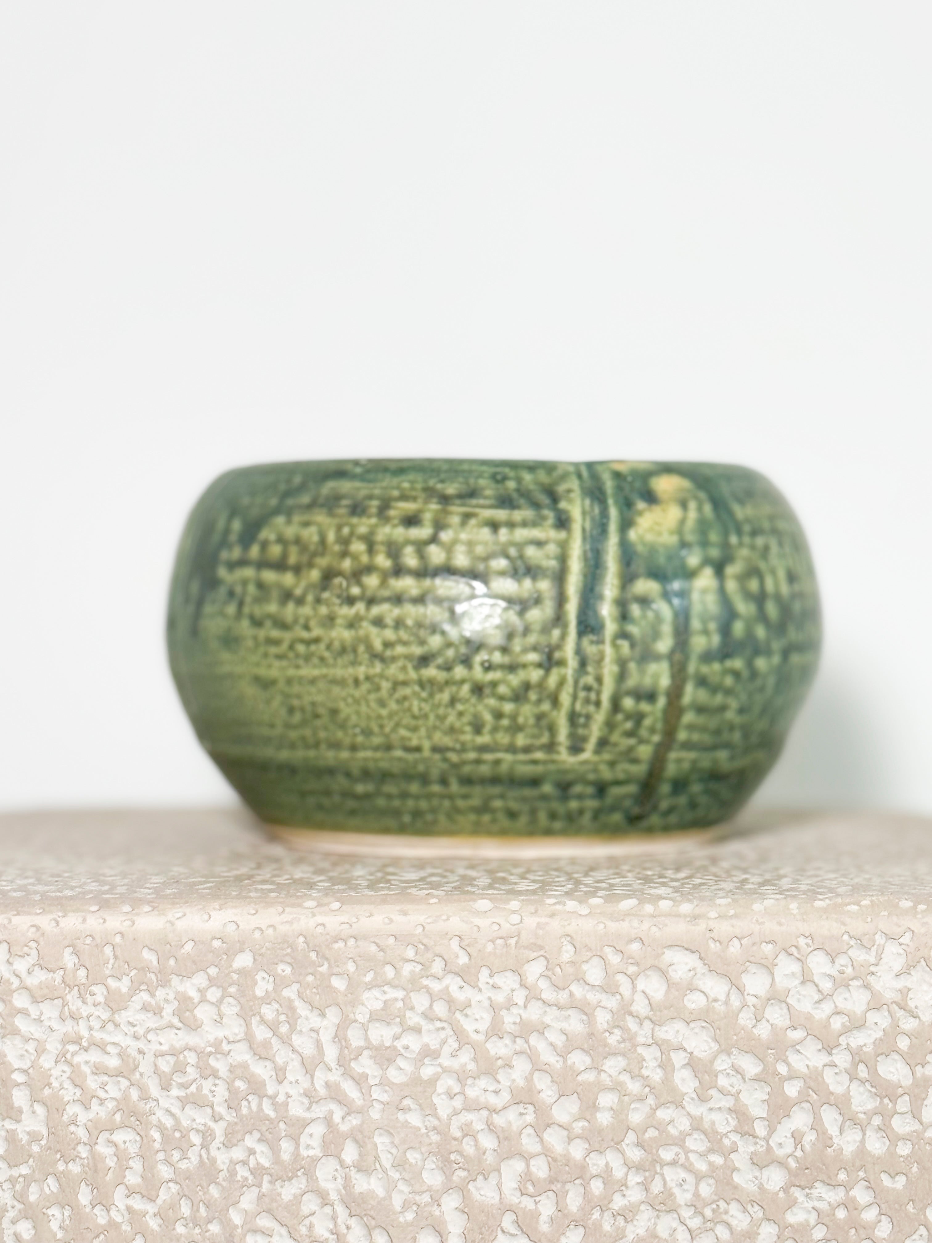 Stunning small, round ceramic vase with a green celadon glaze and a textured chattered pattern.