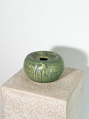 Stunning small, round ceramic vase with a green celadon glaze and a textured chattered pattern.