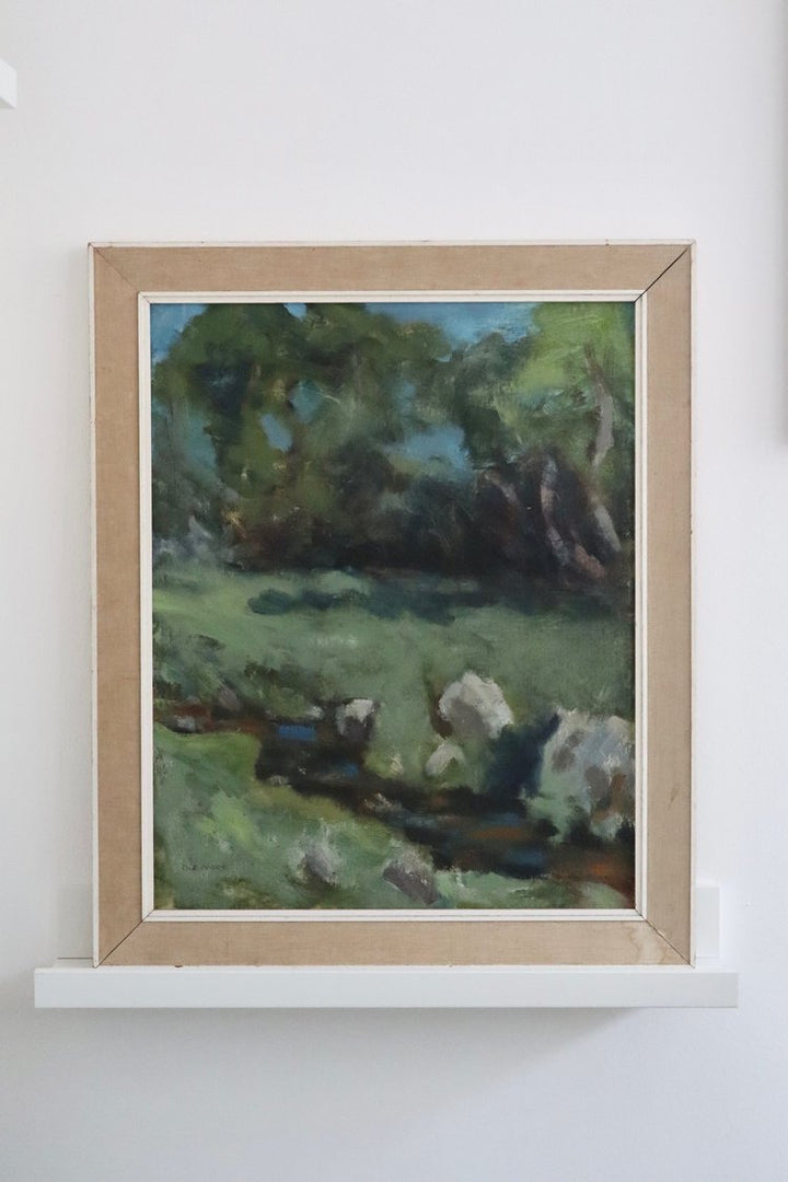 Framed painting of a landscape with trees and people on a white wall