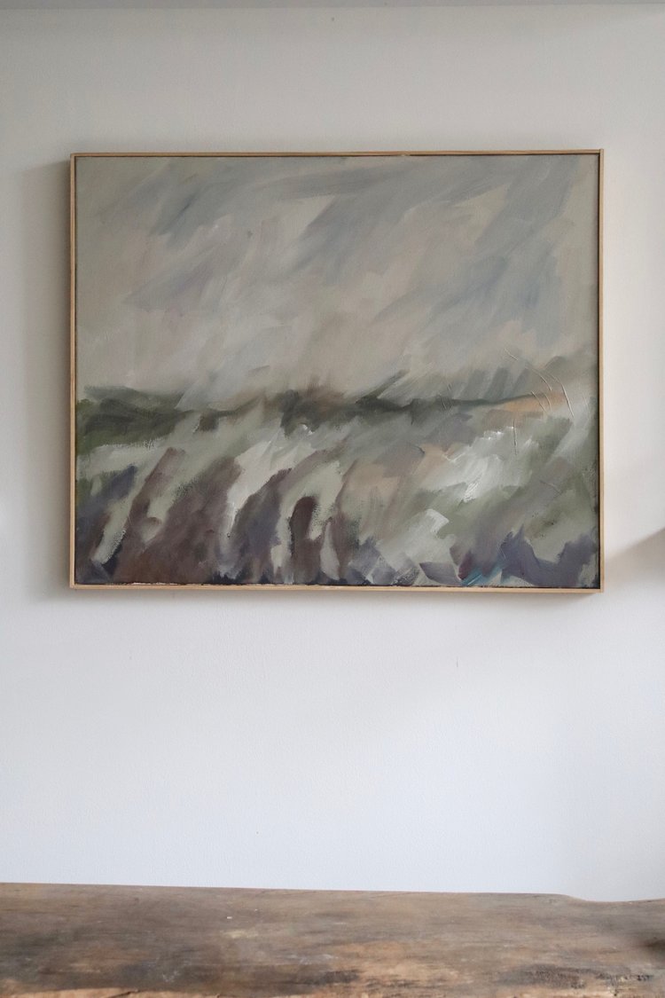 Abstract painting on a white wall with a wooden frame.