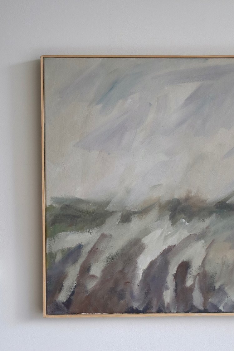 Abstract painting in a gold frame on a light gray wall