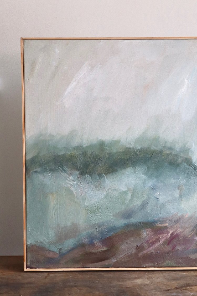 Abstract painting with a gold frame on a wooden surface
