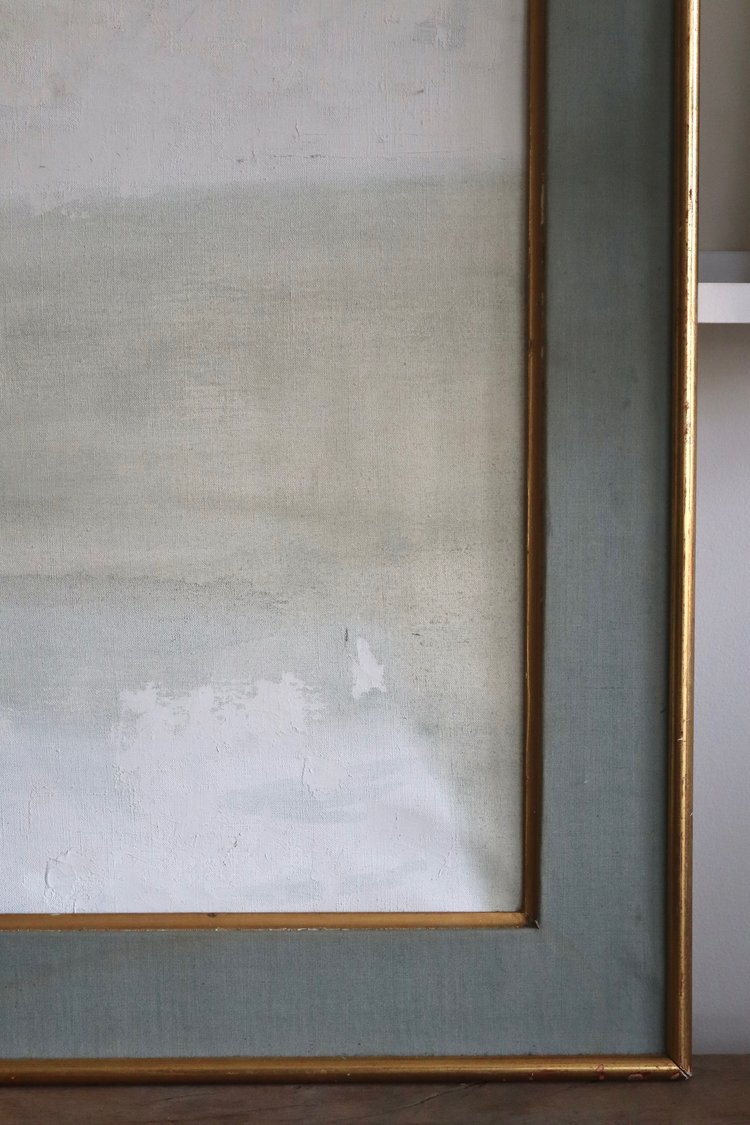 Framed abstract painting with a gold frame on a neutral background