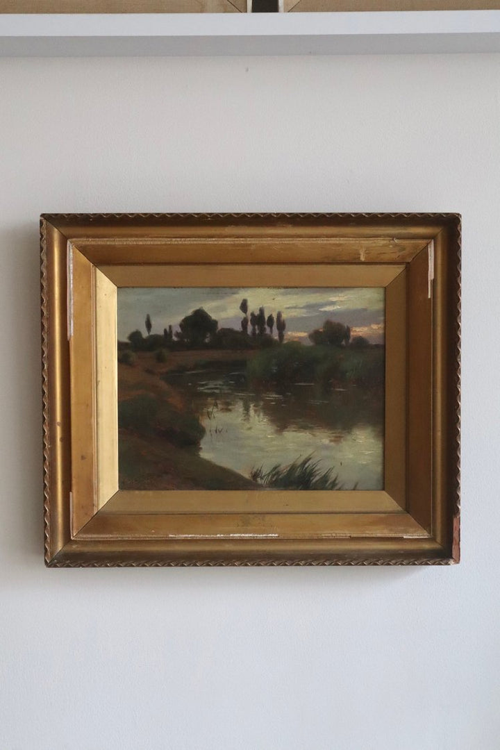 Framed painting of a landscape with a river on a white wall
