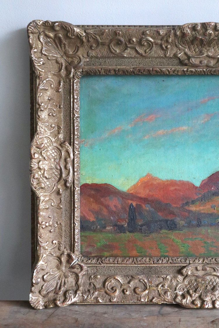 Decorative silver frame with a painting of mountains and sky.