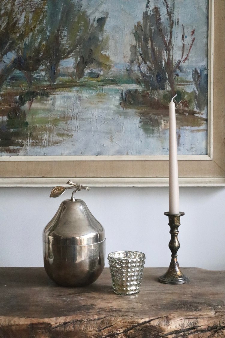Decorative items on a wooden surface with a painting in the background