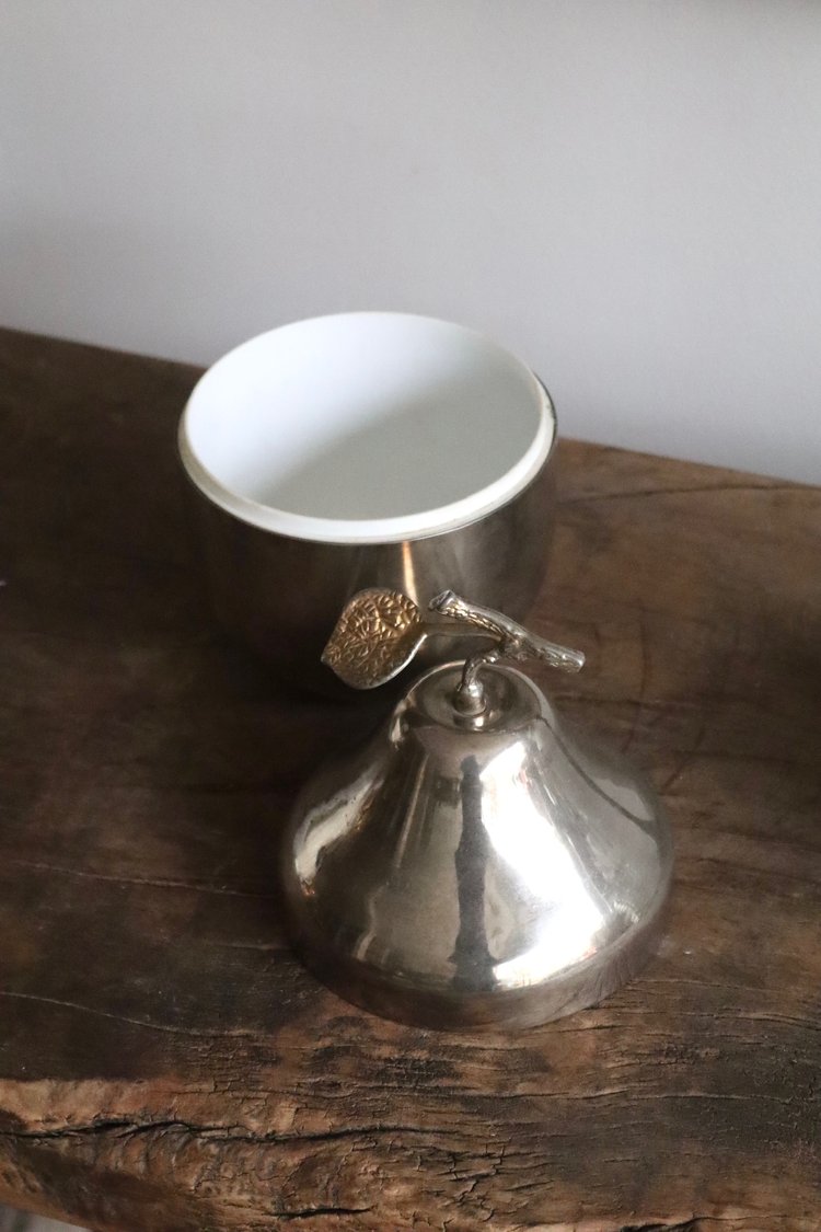 Metallic bell with a white ceramic top on a wooden surface