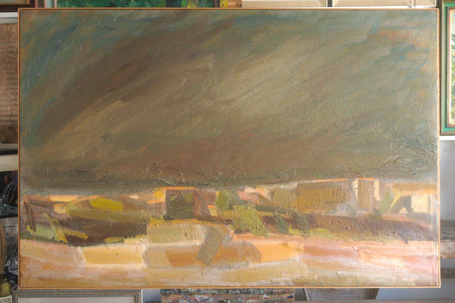 Abstract painting with a large green and brown area on an easel.