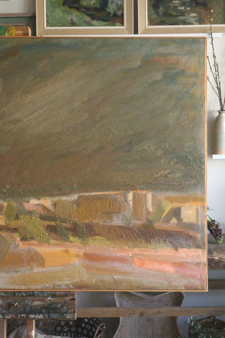 Painting of a landscape with houses and fields on an easel.