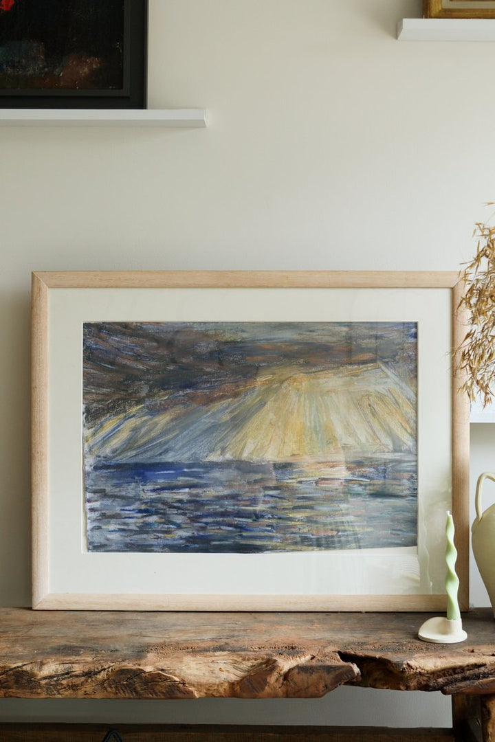Framed abstract painting on a wooden surface with a neutral background