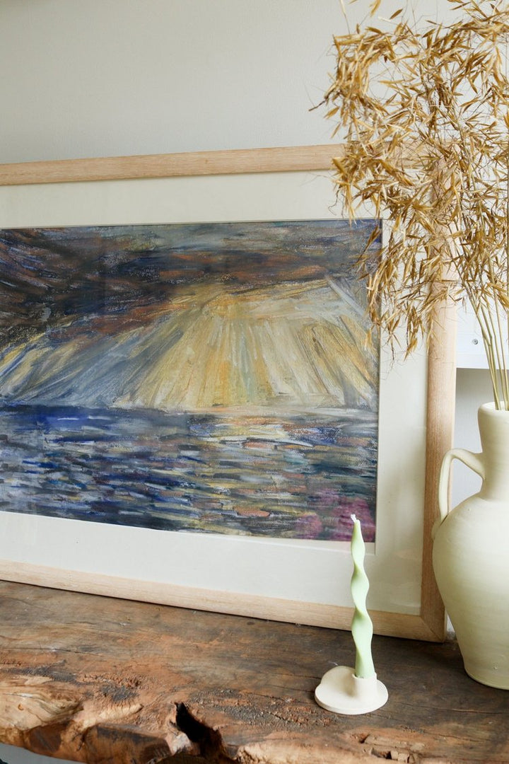 Framed abstract painting on a wooden surface with a vase and plant