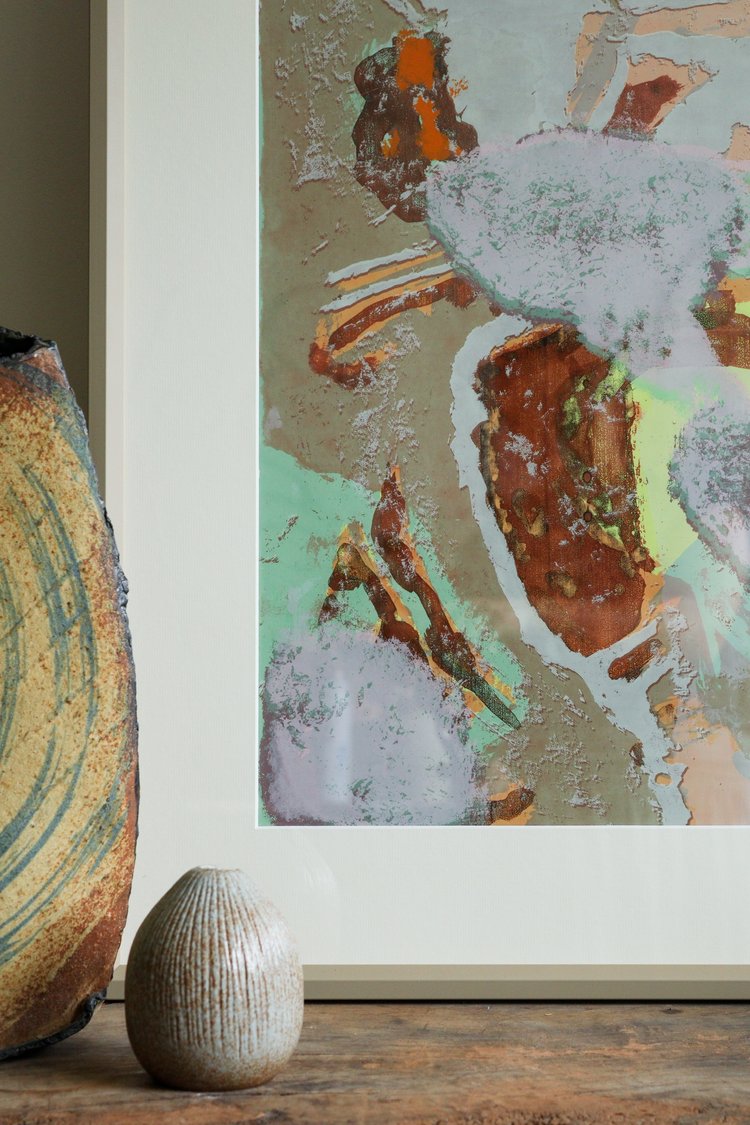 Abstract art print on a wall with two ceramic vases below.