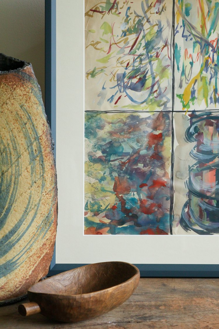 Abstract art print on a wall with a wooden bowl and decorative item below.