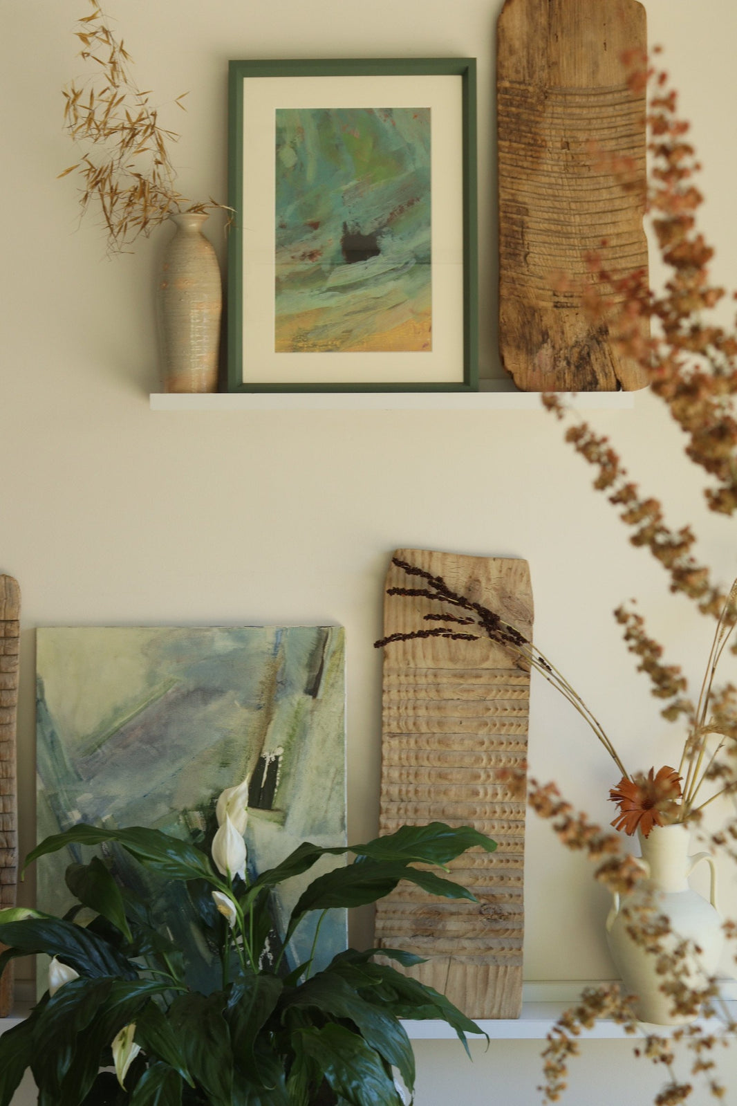 Decorative wall with framed artwork, a plant, and wooden planks.