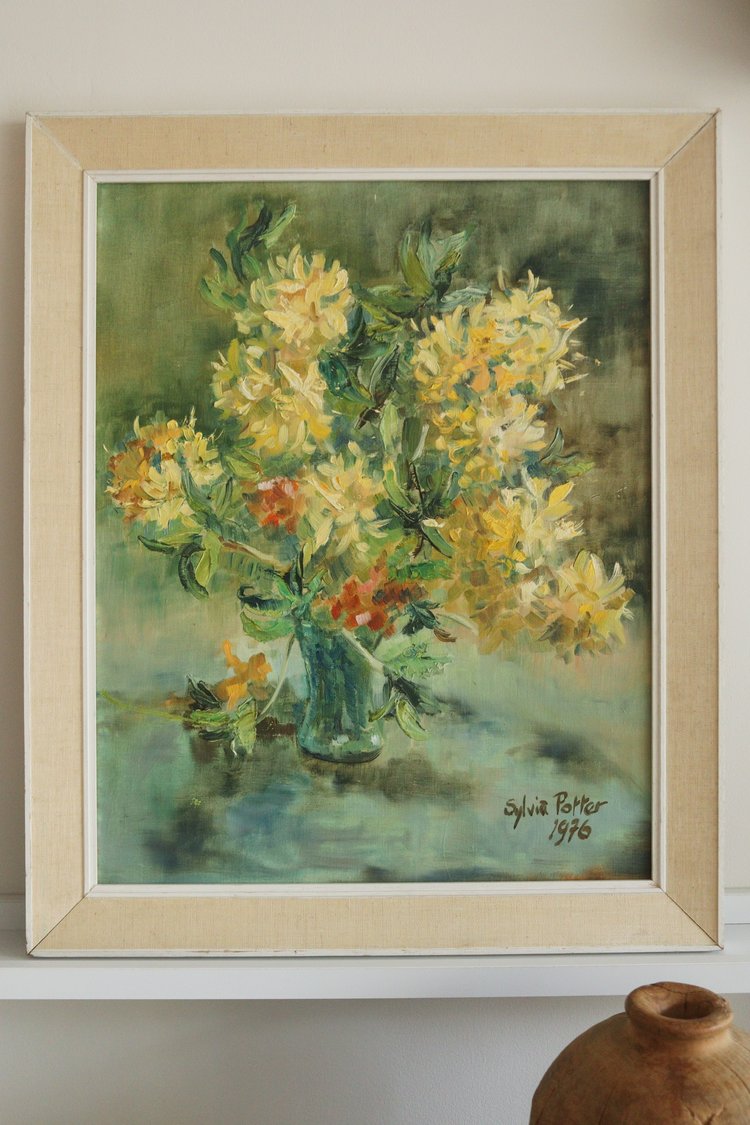 Framed painting of a floral arrangement with a signature and year on a wall.