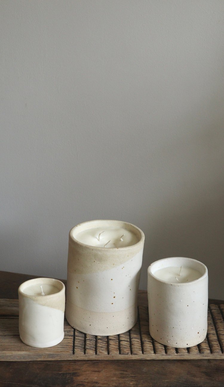 Three ceramic pots of varying sizes on a wooden surface with a neutral background