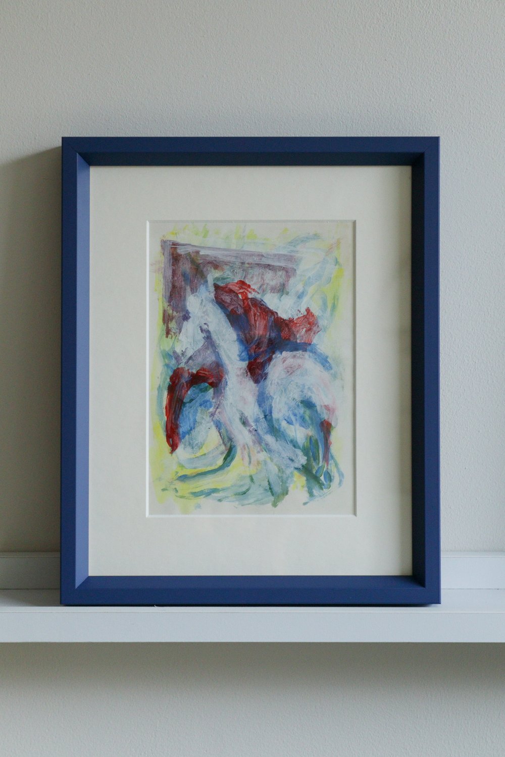 Framed abstract painting with a blue frame on a white surface