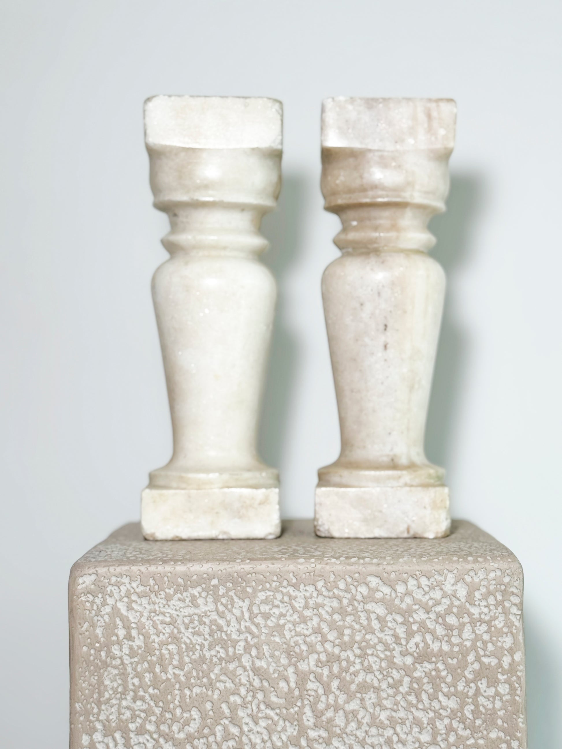 Beautiful pair of aged, handcrafted marble balusters. These are the perfect candle holders. Worn - as seen in images with one baluster showing repairs.