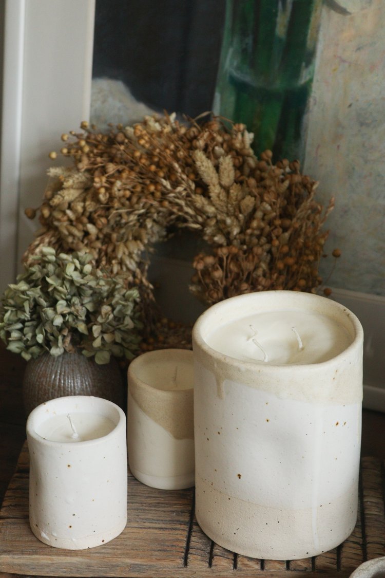 Set of white candles on a wooden surface with decorative elements.