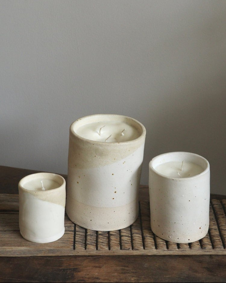 Three ceramic pots of varying sizes on a wooden surface with a neutral background