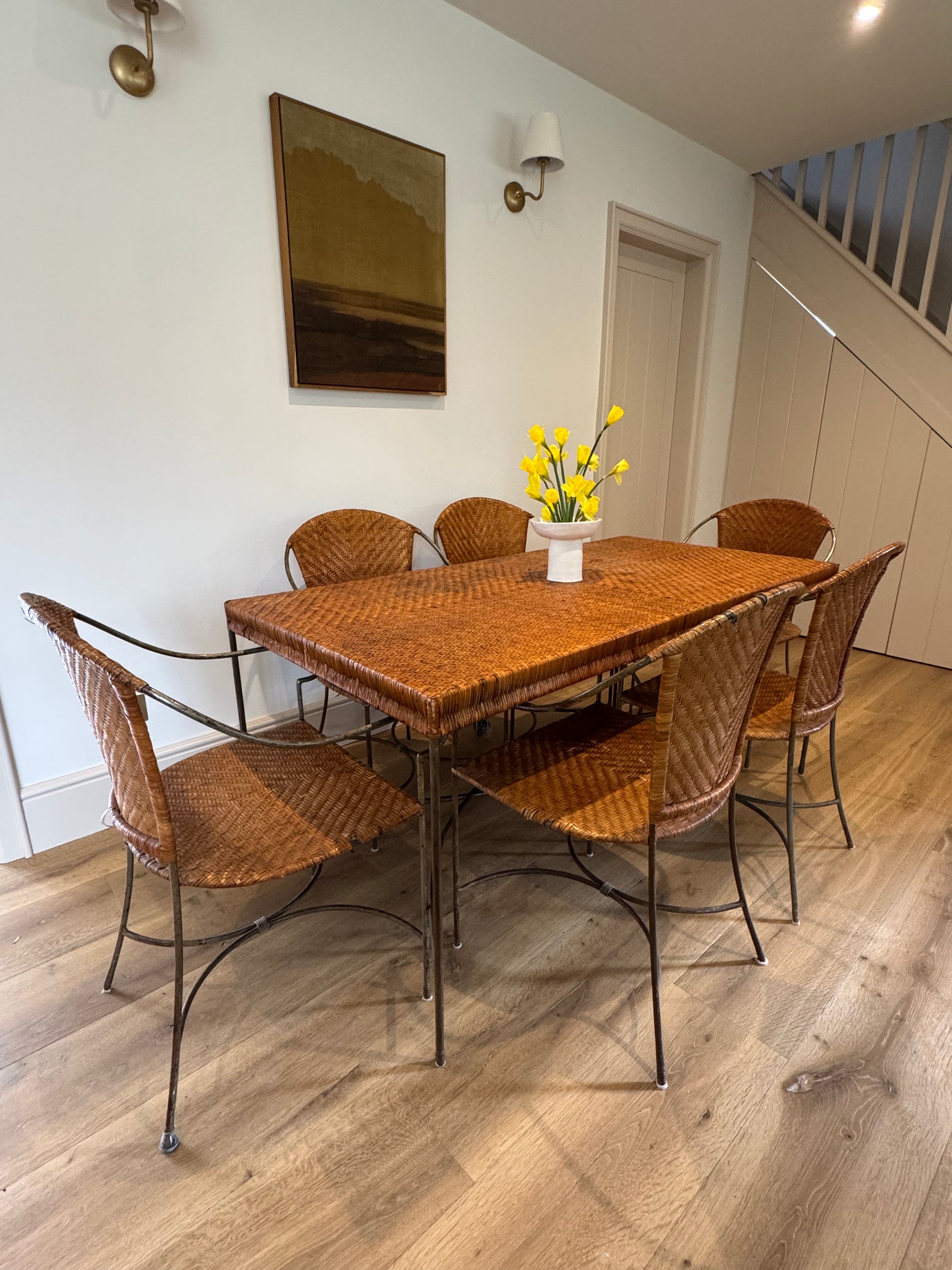 Curated vintage rattan dining set with six chairs. Warm honey tones and sculptural metal base - ideal for refined, design-led interiors.
