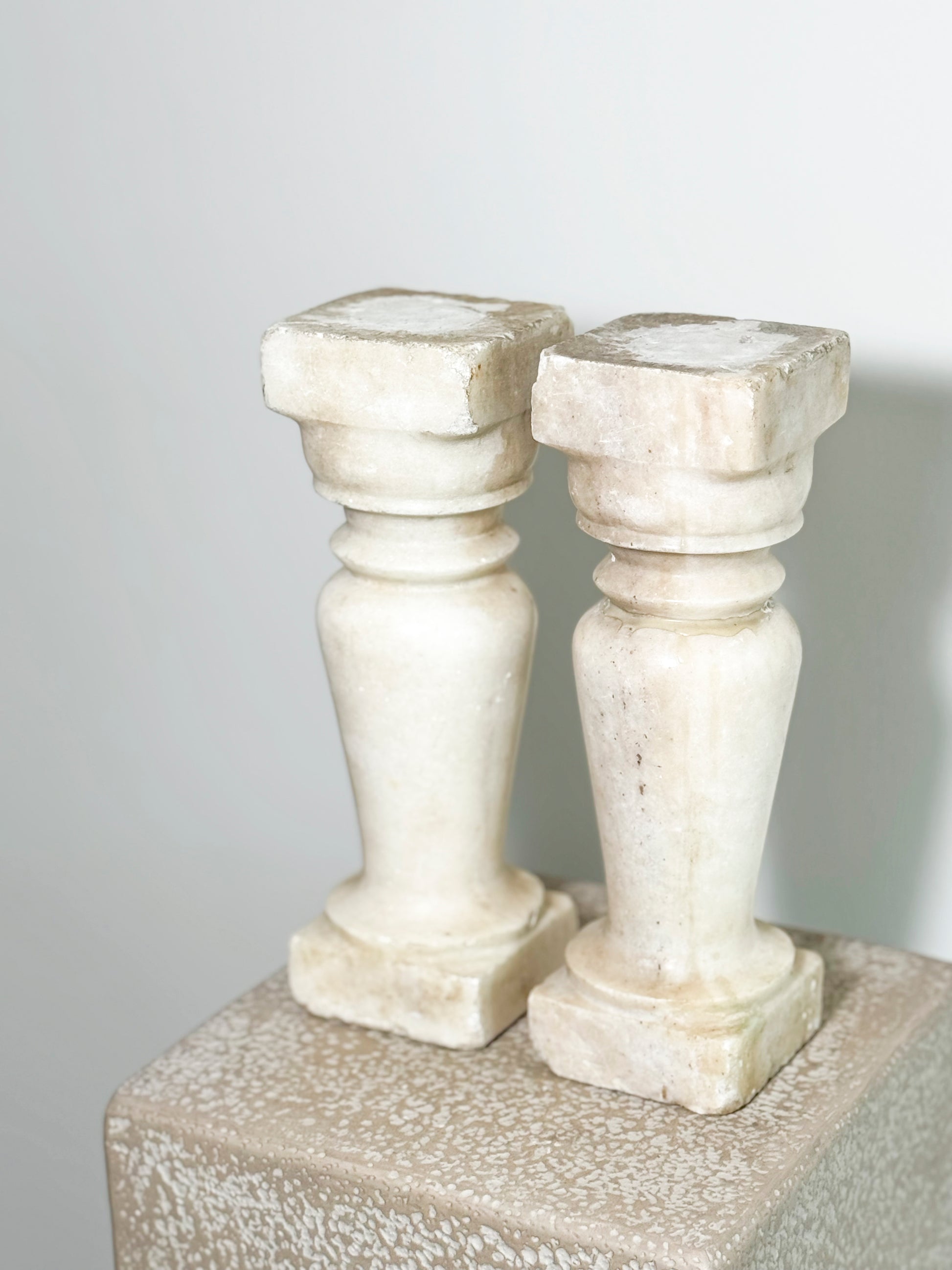 Beautiful pair of aged, handcrafted marble balusters. These are the perfect candle holders. Worn - as seen in images with one baluster showing repairs.